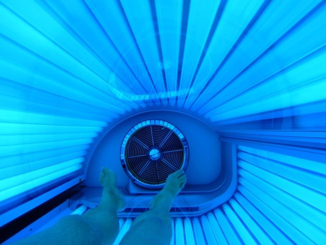 person laying in a tanning bed getting a base tan